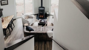 Ein modernes Schlafzimmer im Loftsstil mit schrägem Dach, großen Fenstern, einem eingebauten Kaminofen, einer Treppe und einer gemütlichen Sitzecke.