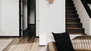 Ein modernes Interieur mit Holzboden, einem Ledersofa, einer Treppe und einem an der Wand befestigten Stierkopf-Kunstwerk.