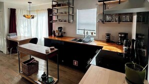 A compact kitchen with a central island, a built-in oven, and a window with blinds. - Newly Renovated Pad Near DT BZN! (Bozeman)