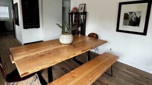 A dining area with a wooden table and bench, a potted plant, and framed pictures on the wall. - Newly Renovated Pad Near DT BZN! (Bozeman)