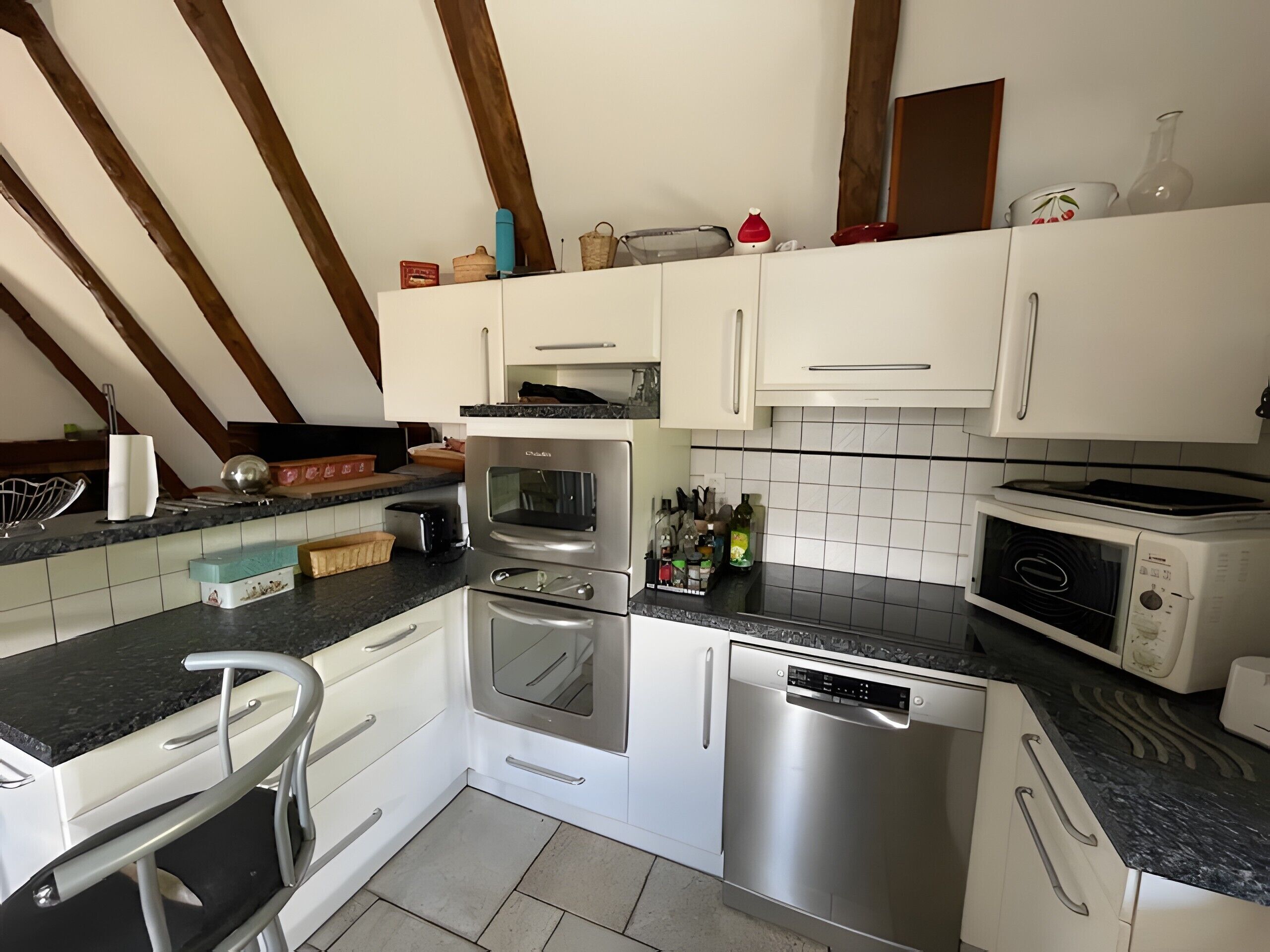A modern kitchen with white cabinets, stainless steel appliances, and a black countertop.