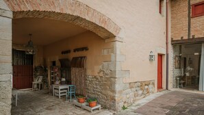 Un edificio in pietra con un ingresso ad arco, una porta in legno, un piccolo tavolo con sedie e piante in vaso.