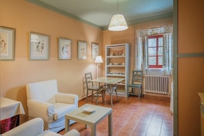 A dining area with a table and chairs, a sofa, a lamp, and framed botanical prints on the wall.
