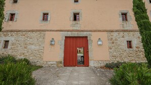 Un edificio con puerta roja, paredes de piedra y varias ventanas.