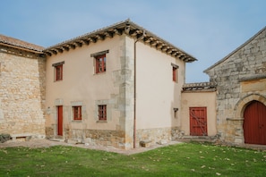 A building with a stone facade, a tiled roof, and a red door.