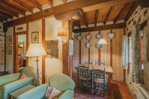 A rustic dining area with wooden beams, a table with chairs, and a wall decorated with plates.