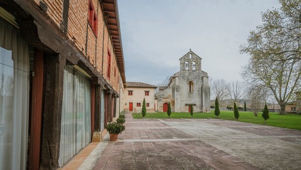 Une cour intérieure avec un bâtiment doté d’un clocher, d’une façade en briques et d’un chemin pavé.