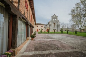 Une cour intérieure avec un bâtiment doté d’un clocher, d’une façade en briques et d’un chemin pavé.