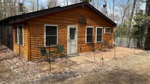 A wooden cabin with a front porch, two windows, and a door. - The Nordico Point Cabin (Ely)