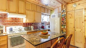 A kitchen with wooden cabinets, a stove, microwave, and a refrigerator. - The Nordico Point Cabin (Ely)