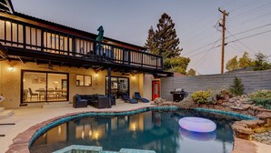 Ein Wohnhaus mit Schwimmbad, Sitzgelegenheiten im Freien und einer überdachten Terrasse.