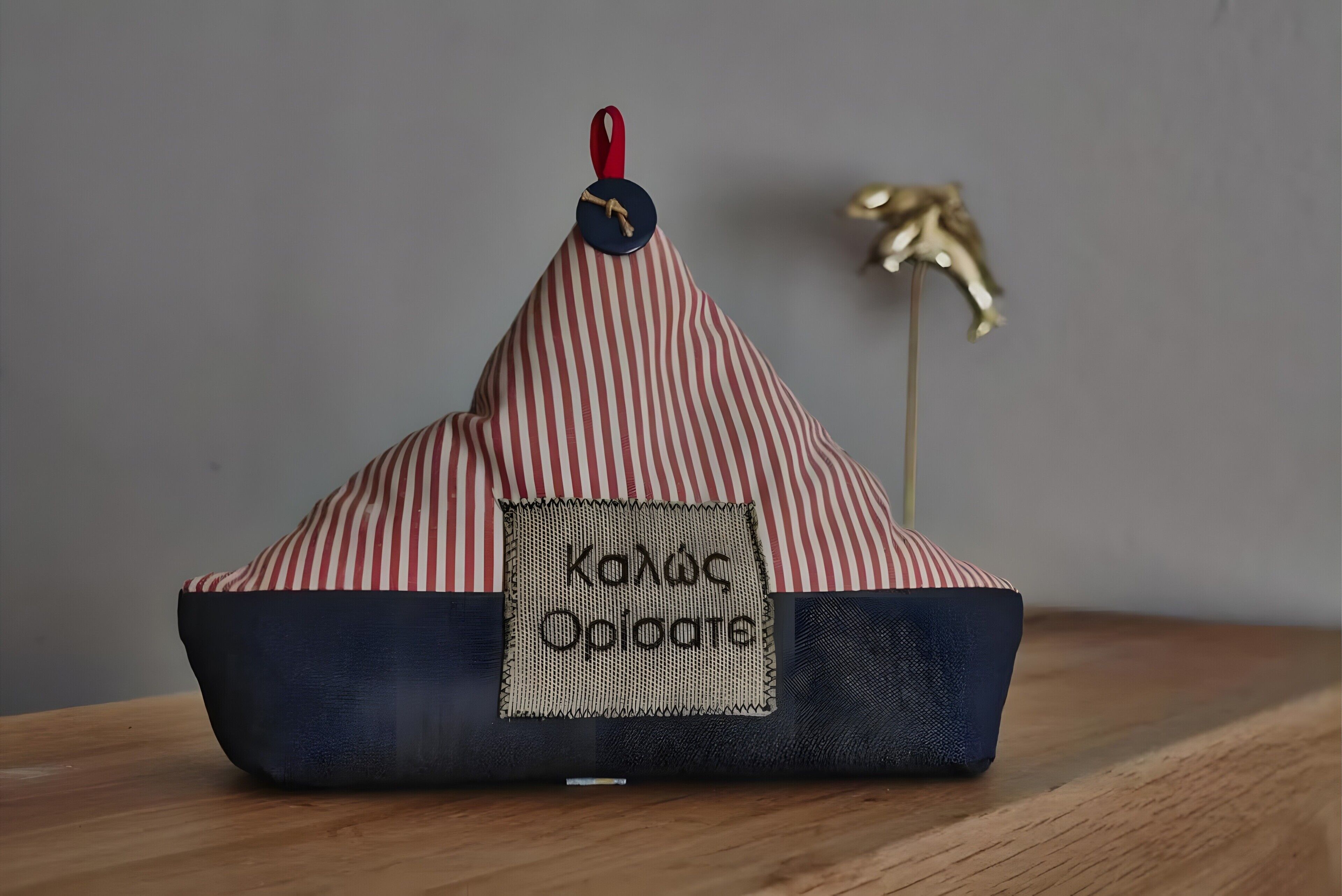 En randig sittpuff i form av en bönsäck, med en etikett som visar texten ”KADOC Opioate”, placerad på en träyta.