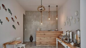 Ein Empfangsbereich mit Holztresen, einer Sitzecke mit Tisch und Stühlen sowie Wanddekorationen, darunter Fische und Teller.