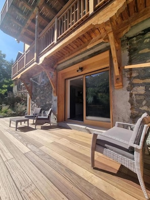 Eine Holzterrasse mit Sitzgelegenheit und einer Steinsäule.
