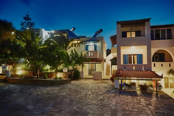 A modern building with satellite dishes, a stone courtyard, and a covered outdoor seating area.