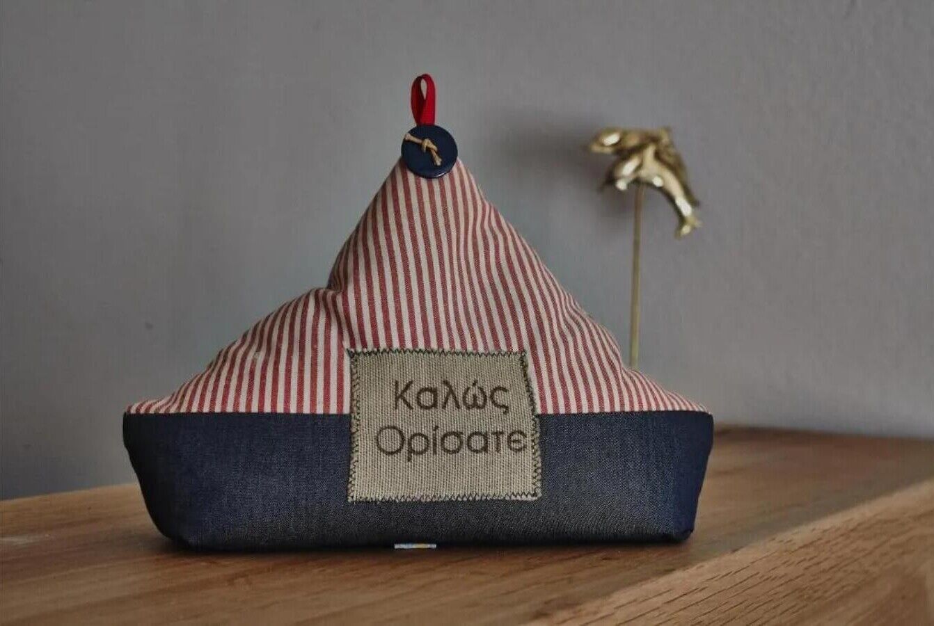 Ein kleines, gestreiftes Objekt mit Stoffbezug und einem Anhänger mit der Aufschrift 'Kahçe Opioate' auf einer Holzoberfläche.