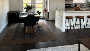 Una cocina amplia con armarios blancos, una isla central con taburetes y una zona de comedor con mesa y sillas.