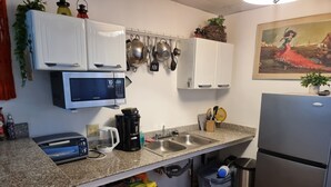 A kitchen with a microwave, sink, and refrigerator. There are cabinets above the counter and a painting on the wall. - Cool Loft, King Bed, in Dolega, 10min to David/20min to Boquete. Private Parking (Dolega)