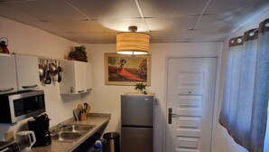 A compact kitchen with a microwave, coffee maker, sink, and a refrigerator. There is a painting on the wall and a door with a window. - Cool Loft, King Bed, in Dolega, 10min to David/20min to Boquete. Private Parking (Dolega)