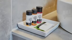 A bathroom shelf with three bottles of olive oil and a small card. - Apartment 'Irene 13 Superior  1' with Sea View, Wi-Fi and Air Conditioning (Andros)