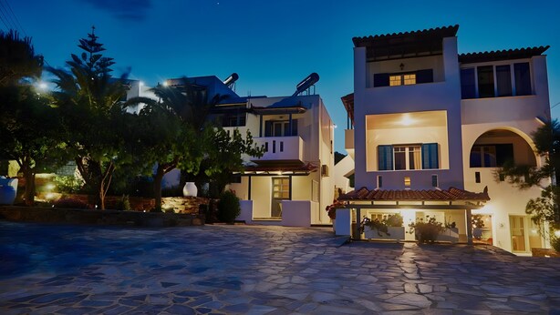 A modern two-story building with a stone-paved courtyard, large windows, and outdoor lighting. - Apartment 'Irene 13 Superior  1' with Sea View, Wi-Fi and Air Conditioning (Andros)