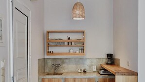 A compact kitchen with a built-in stove, wooden cabinets, a hanging light fixture, and a coffee maker on the countertop. - Studio Apartment 'Irene 5 Standard Double 2' with Sea View, Wi-Fi and Air Conditioning (Andros)
