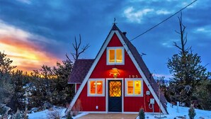 Un edificio de techo triangular rojo con el número '195' en la fachada, rodeado de nieve y árboles.