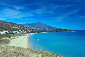 Eine Küstenlandschaft mit Strand, Berg und einer kleinen Siedlung.