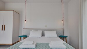 A bedroom with a bed, two bedside tables, a wardrobe, and pendant lights. - Studio Apartment 'Irene Standard Double 10' with Sea View, Wi-Fi and Air Conditioning (Andros)
