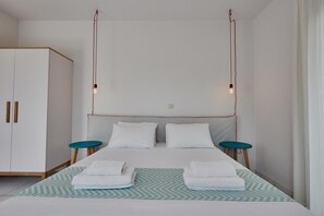 Un dormitorio con una cama, dos mesitas de noche, un armario y lámparas colgantes.