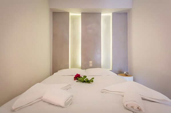 A hotel room with a neatly made bed, a bedside table with a lamp, and a wall-mounted light fixture.