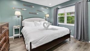 A bedroom with a bed, two bedside tables, a dresser, a window with curtains, and wall-mounted fish decorations.
