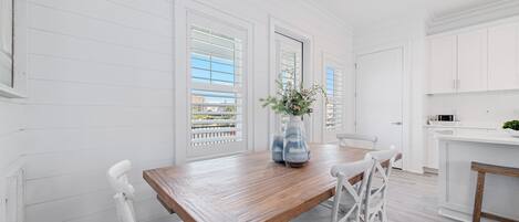 Una cocina moderna con armarios blancos, una mesa de comedor de madera y sillas blancas.
