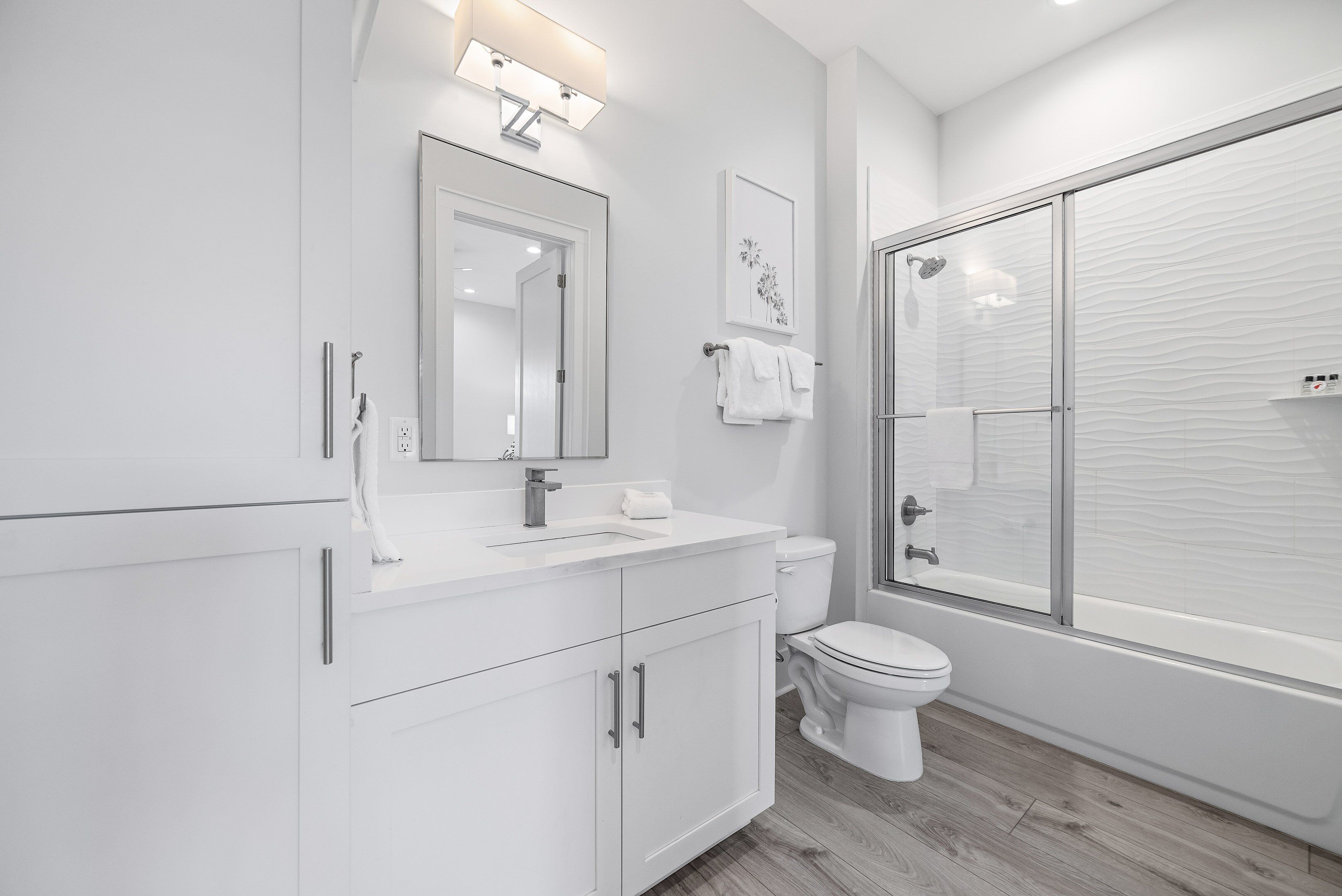 Un baño moderno con un tocador blanco, un inodoro y una ducha con cerramiento de vidrio.