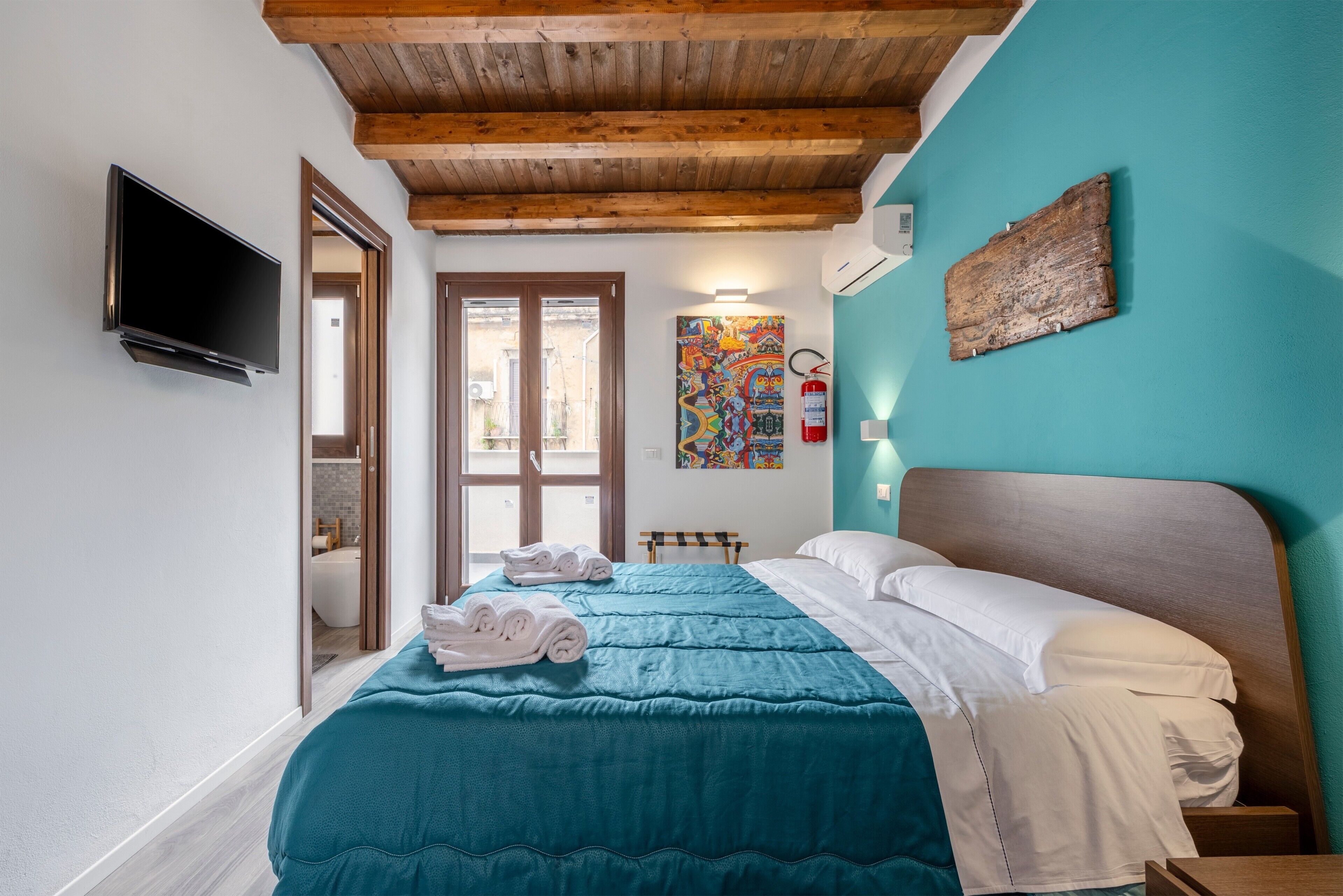 Una camera da letto con un letto, una televisione, un estintore e un quadro appeso al muro.