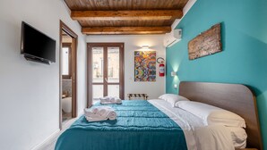 A bedroom with a bed, a television, a fire extinguisher, and a painting on the wall. - Casa Vicolo San Giovanni Apartment with Private Terrace, Wi-Fi & Air Conditioning (Palermo)