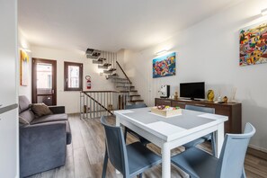 Un salon moderne comprenant un canapé, une table à manger, des chaises, un téléviseur et un escalier.