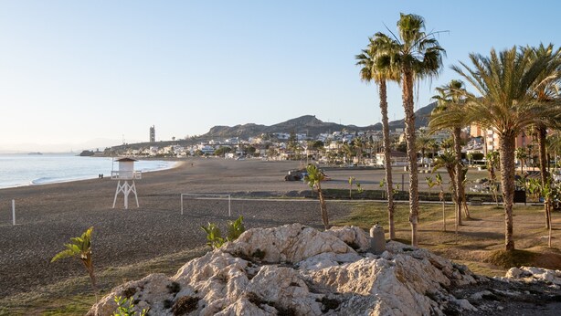A beach with a lifeguard tower, palm trees, and a distant mountain. - Apartment 'Casa Santo Front Beach' with Private Terrace and Wi-Fi (Cala del Moral)