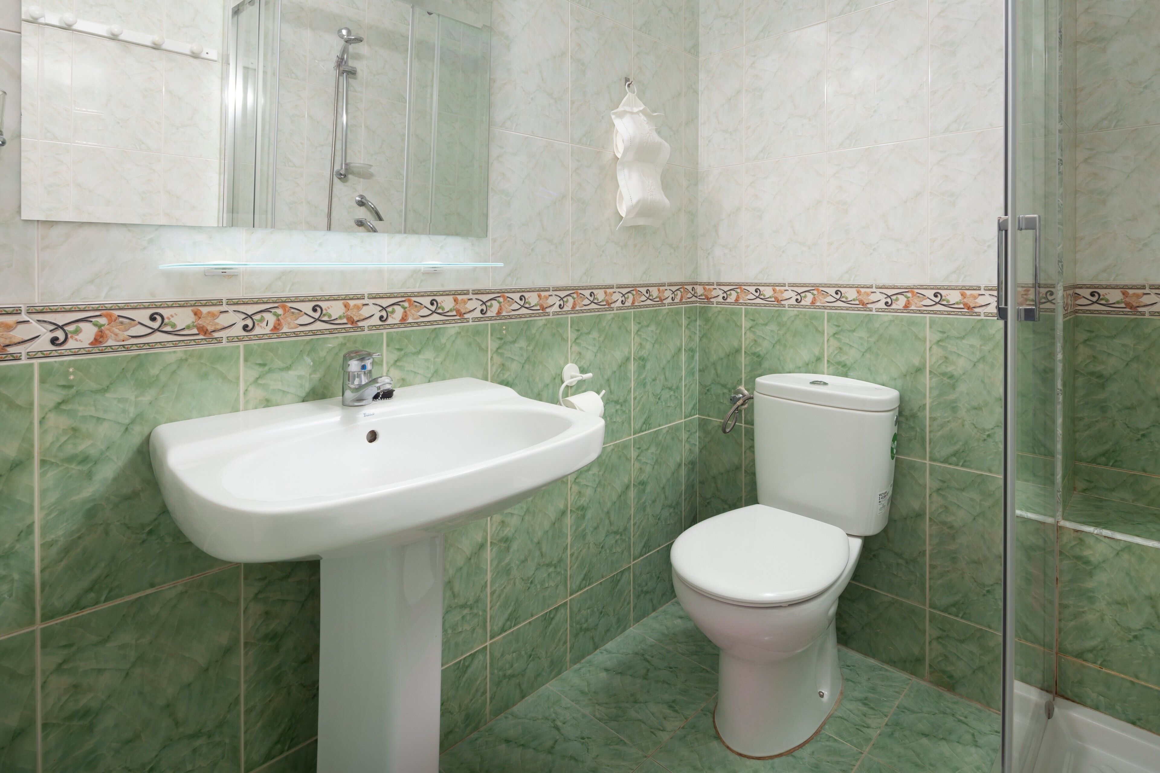 Une salle de bain comprenant un lavabo, des toilettes et un espace douche.