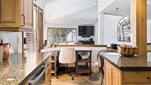 Eine moderne Küche mit Granit Arbeitsplatte, Holzschränken und einer großen Kochinsel mit Spüle und Sitzgelegenheit.