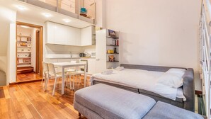 A compact bedroom with a bed, a desk, and a chair. There is a staircase leading to an upper level. - Cozy flat in Isola facing Bosco Verticale - Intrho (Milan)