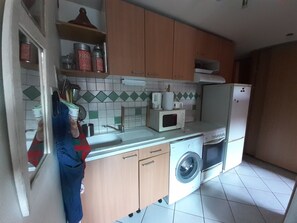 A kitchen with a washing machine, microwave, and cabinets.