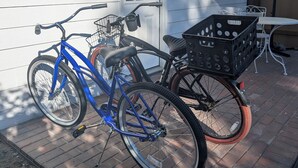 A blue bicycle and a tricycle with a basket parked against a white house. - Charming Cottage in Central Salem (Salem)