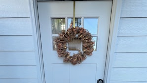 A white door with a wreath, a doormat with "HOME" written on it, and a garage door in the background. - Charming Cottage in Central Salem (Salem)