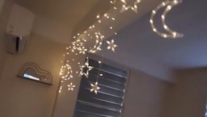 A room with a slanted ceiling, a window with horizontal blinds, and string lights with star and crescent shapes. - 3-bedroom in superb cozy Arecibo River with WiFi, AC (Puerto Rico)
