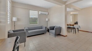 A spacious living area with a grey sofa, a smaller armchair, and a dining table with chairs. - 3-bedroom in superb cozy Arecibo River with WiFi, AC (Puerto Rico)