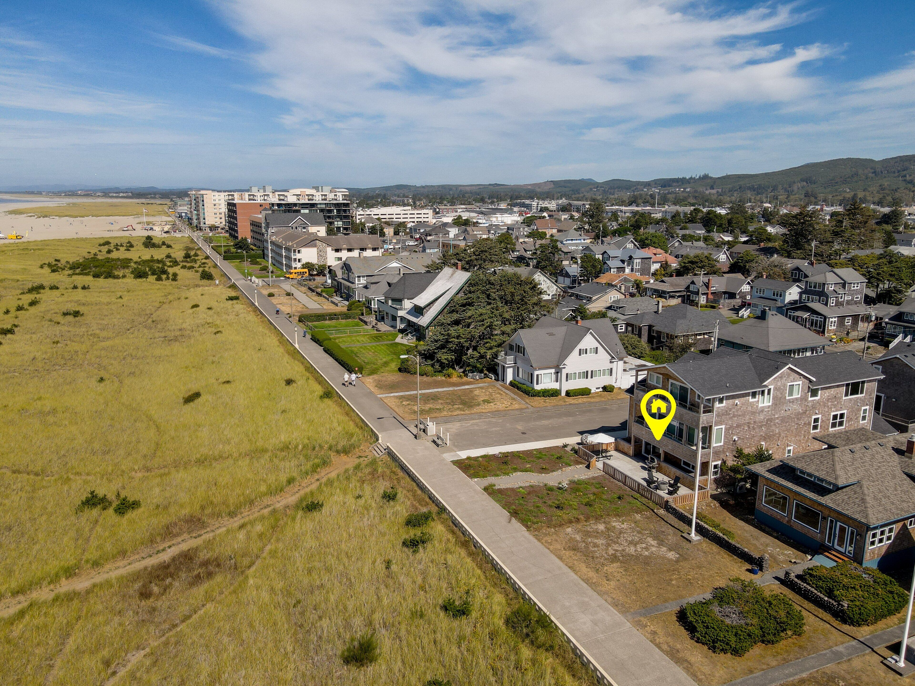 Vista aérea de una zona residencial con casas, una carretera y una playa al fondo.