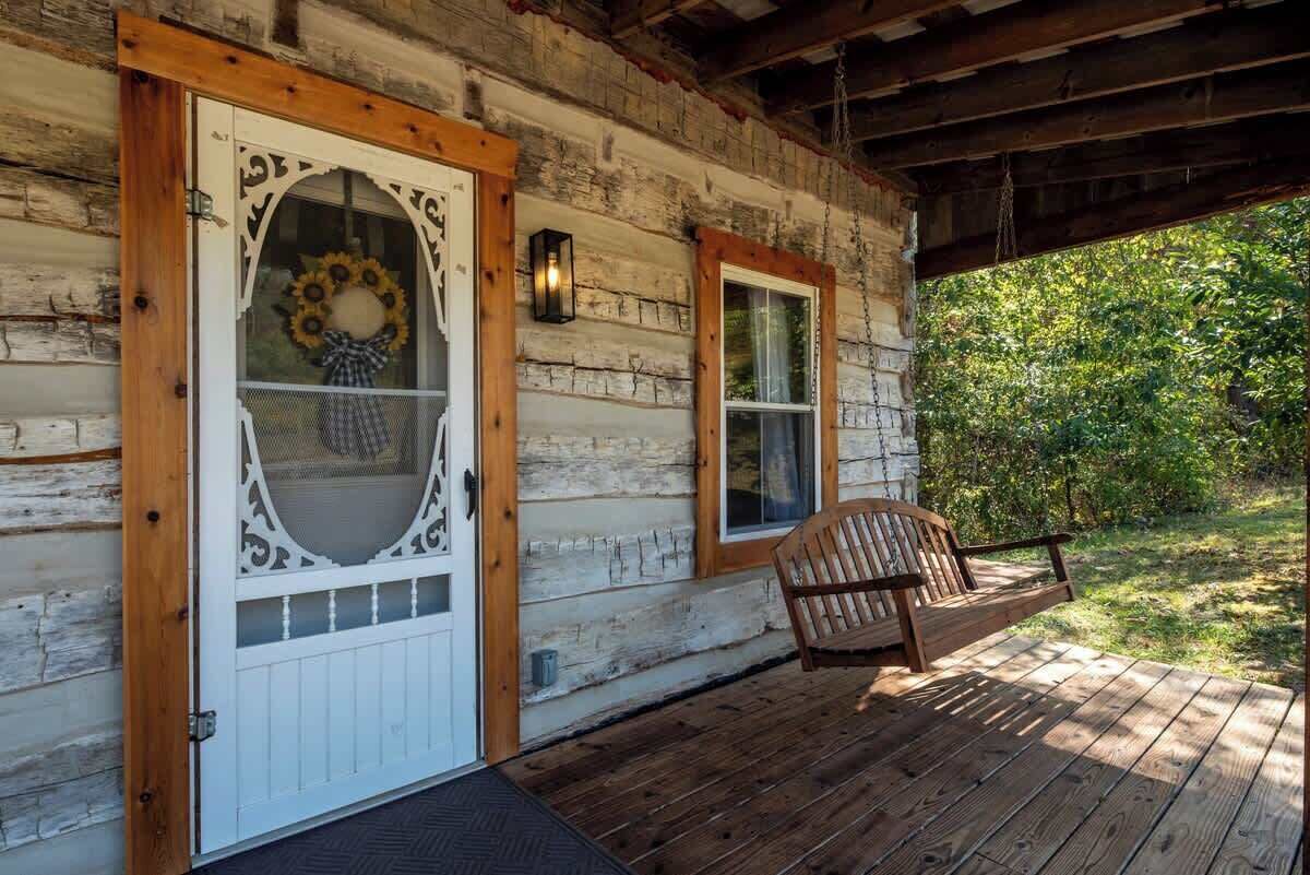 A wooden cabin with a porch, a white door with a decorative wreath, and a wooden chair.