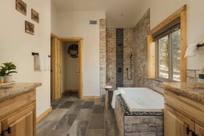 A bathroom with a stone wall, a bathtub, a shower, and a window.