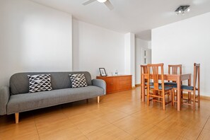 A living room with a grey sofa, wooden dining table, and chairs.
